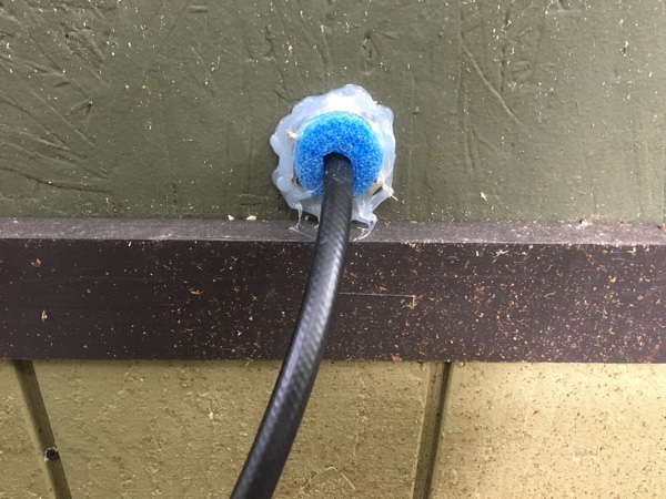 I cut a small hole for the propane hose using a hole saw, ran the hose through it, and filled the gap with a pool noodle scrap and a thick bead of silicone.